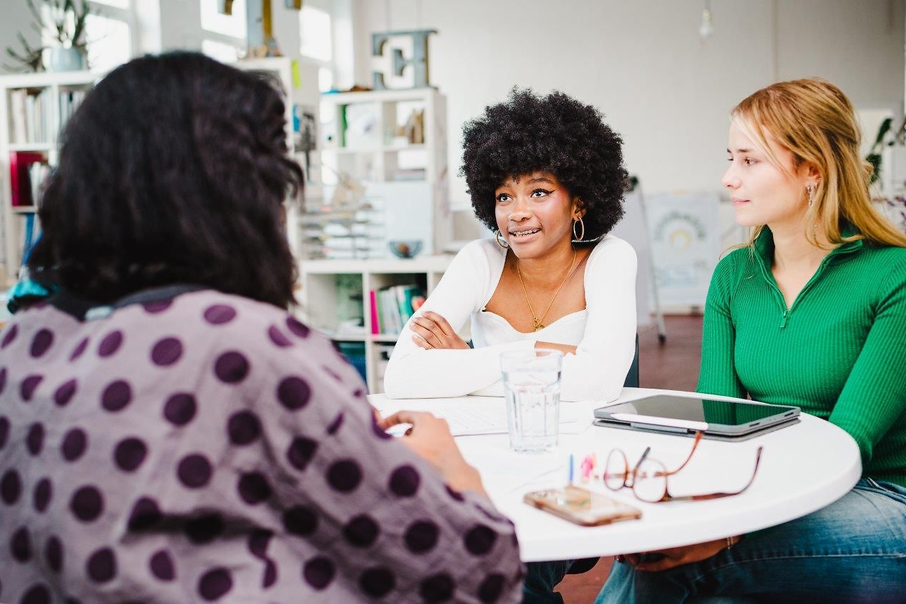 Drei junge Frauen sitzen an einem Tisch