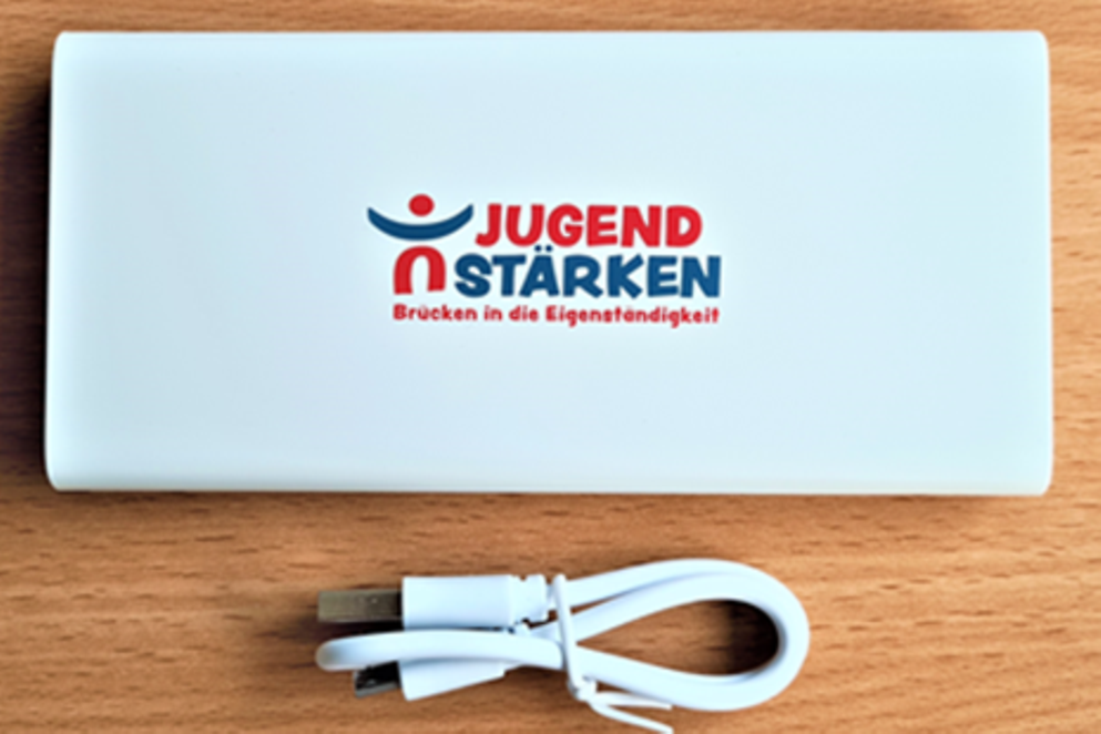 Ein Foto der Powerbank mit dem Aufdruck "Jugend Stärken Brücken in die Eigenständigkeit"